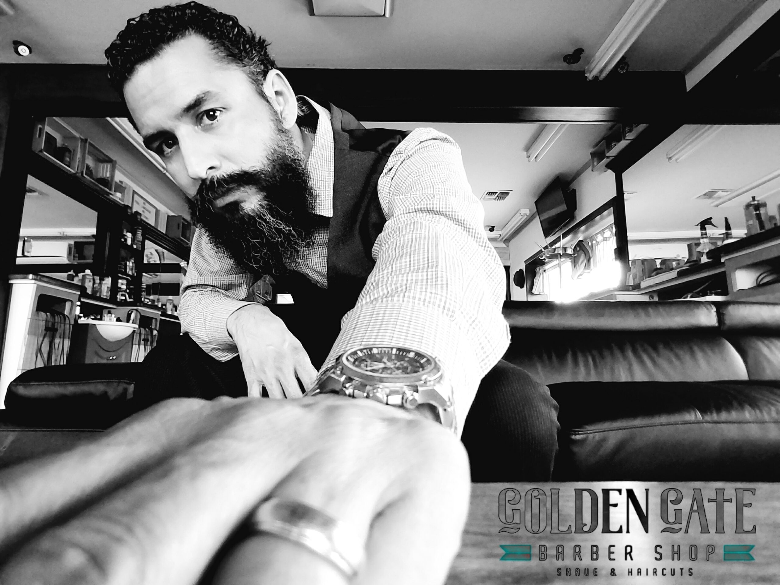 A man with a beard and tattoos sitting on top of a couch.